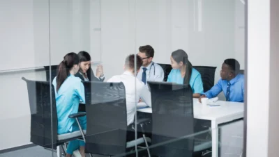 Profissionais da saúde reunidos em sala de reunião dentro de um coworking da saúde, discutindo gestão, processos e colaboração entre clínicas e especialidades.